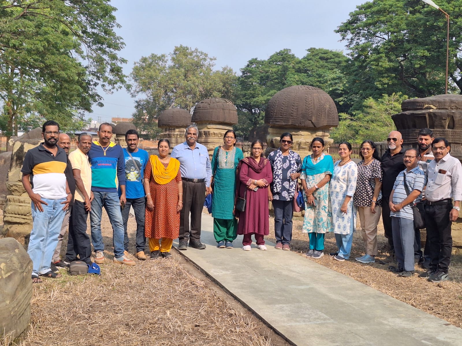 The full Kerala group posing together at an ancient carved-stone temple site in the plains of Assam