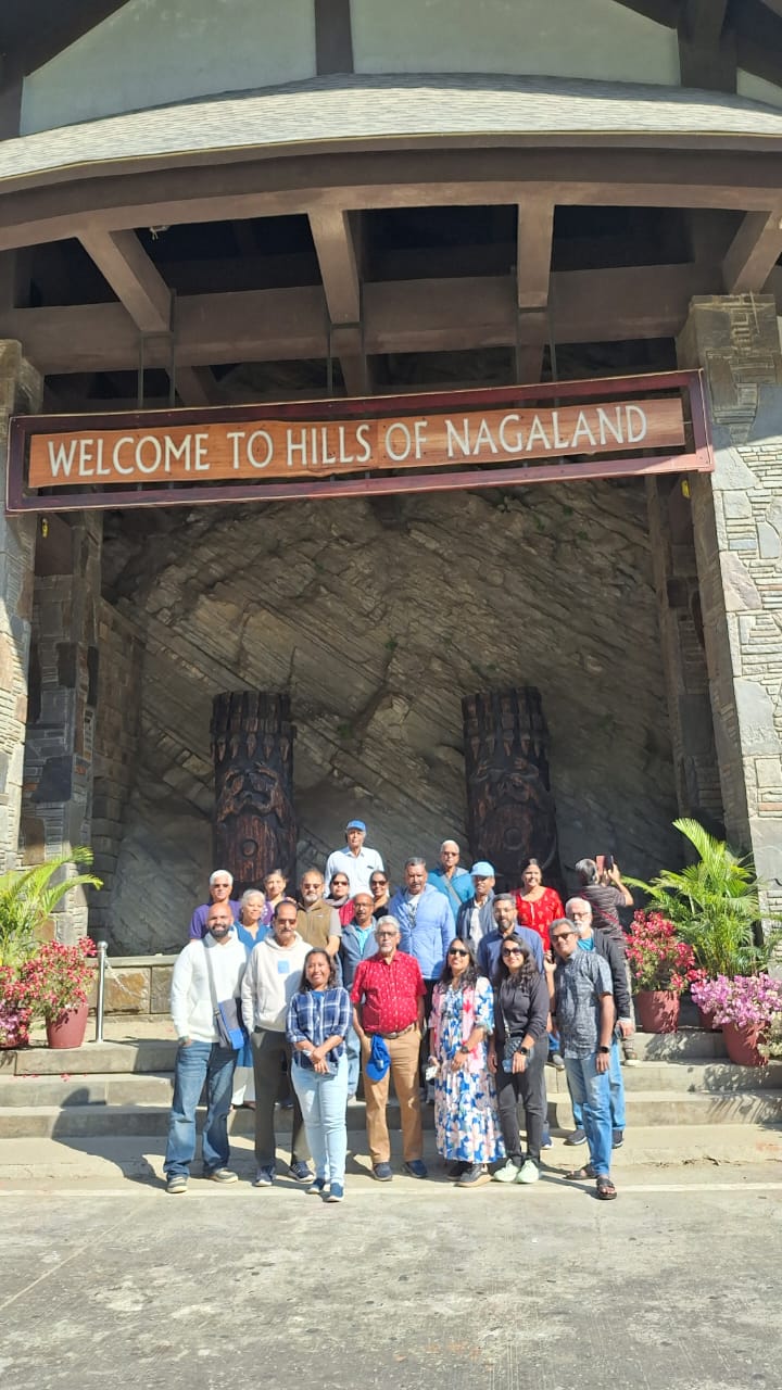 The Kerala group posing under the ceremonial 'Welcome to the Hills of Nagaland' entry gate, with two large carved wooden warrior columns behind them