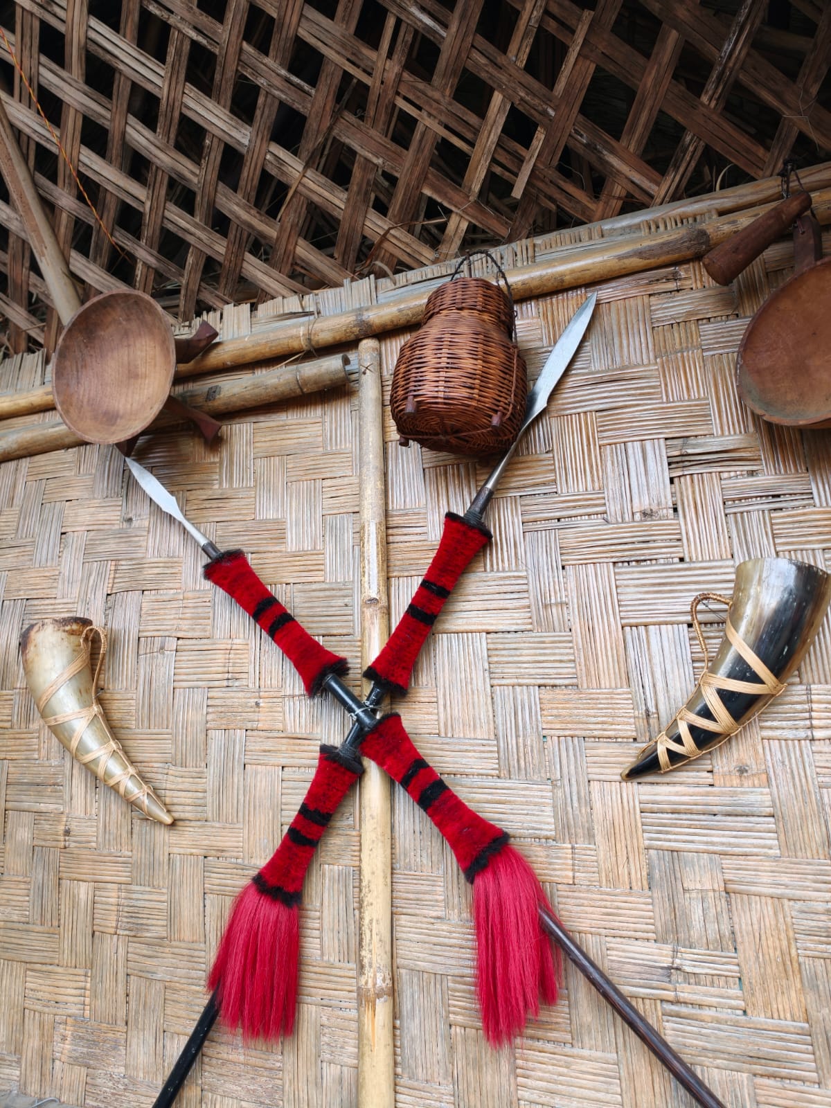 Interior of a Naga morung at Kisama Heritage Village with crossed ceremonial spears, mithun horns and woven bamboo walls