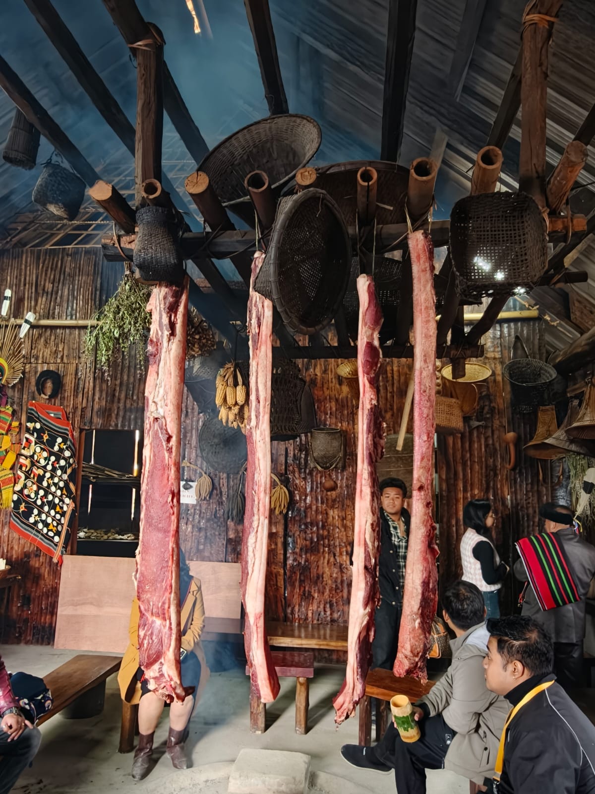 Interior of a Naga morung at Kisama with sides of pork smoking from bamboo rafters