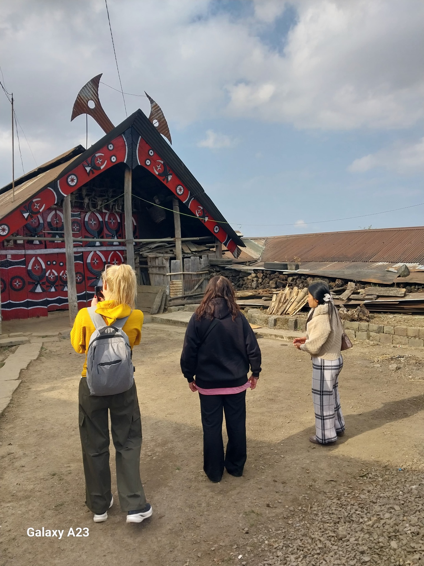 Painted red-and-black Angami morung at Khonoma village with mithun-horn roof finials